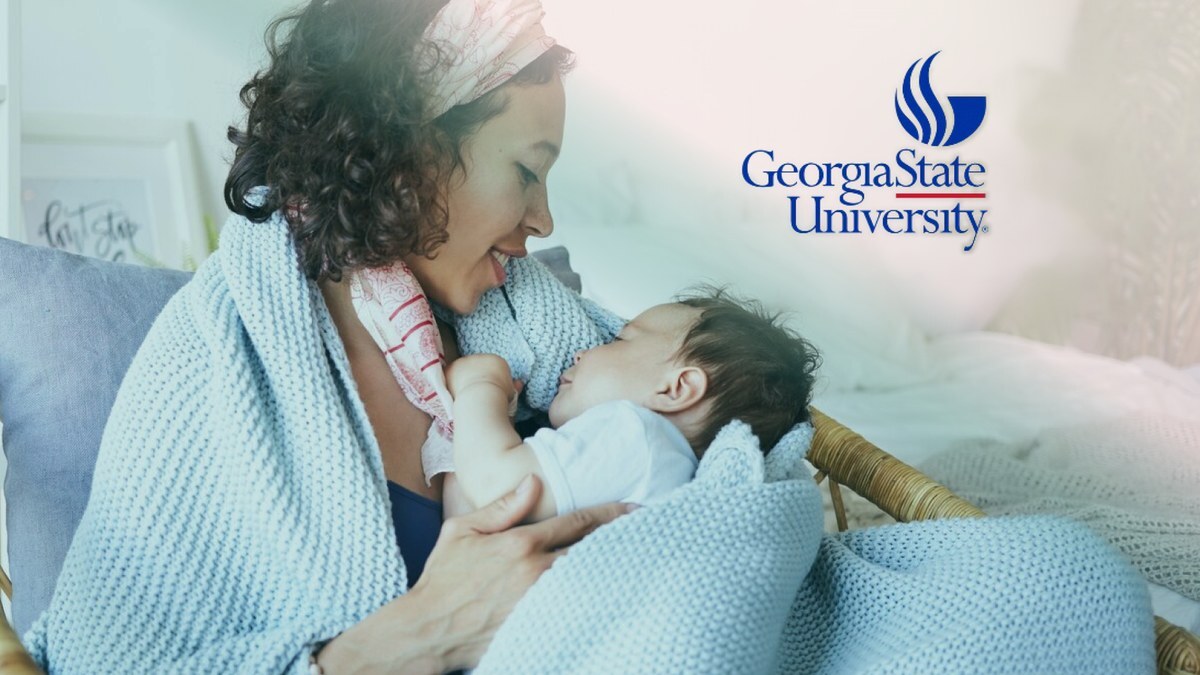 A smiling mother holding her sleeping baby wrapped in a soft blue blanket, with the Georgia State University logo