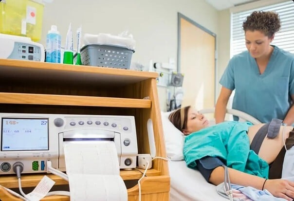 An in-clinic NST: a nurse with an expectant mother on a bedside CTG monitor
